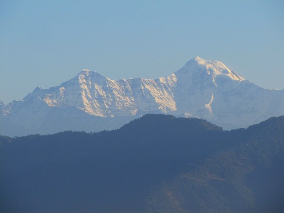 Snow-capped mountains against a clear blue sky with ridges in the foreground.